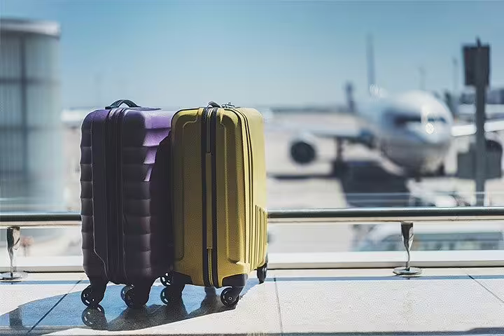 Colorful suitcases at airport terminal window with plane ready for departure before private transfer Positano to Rome