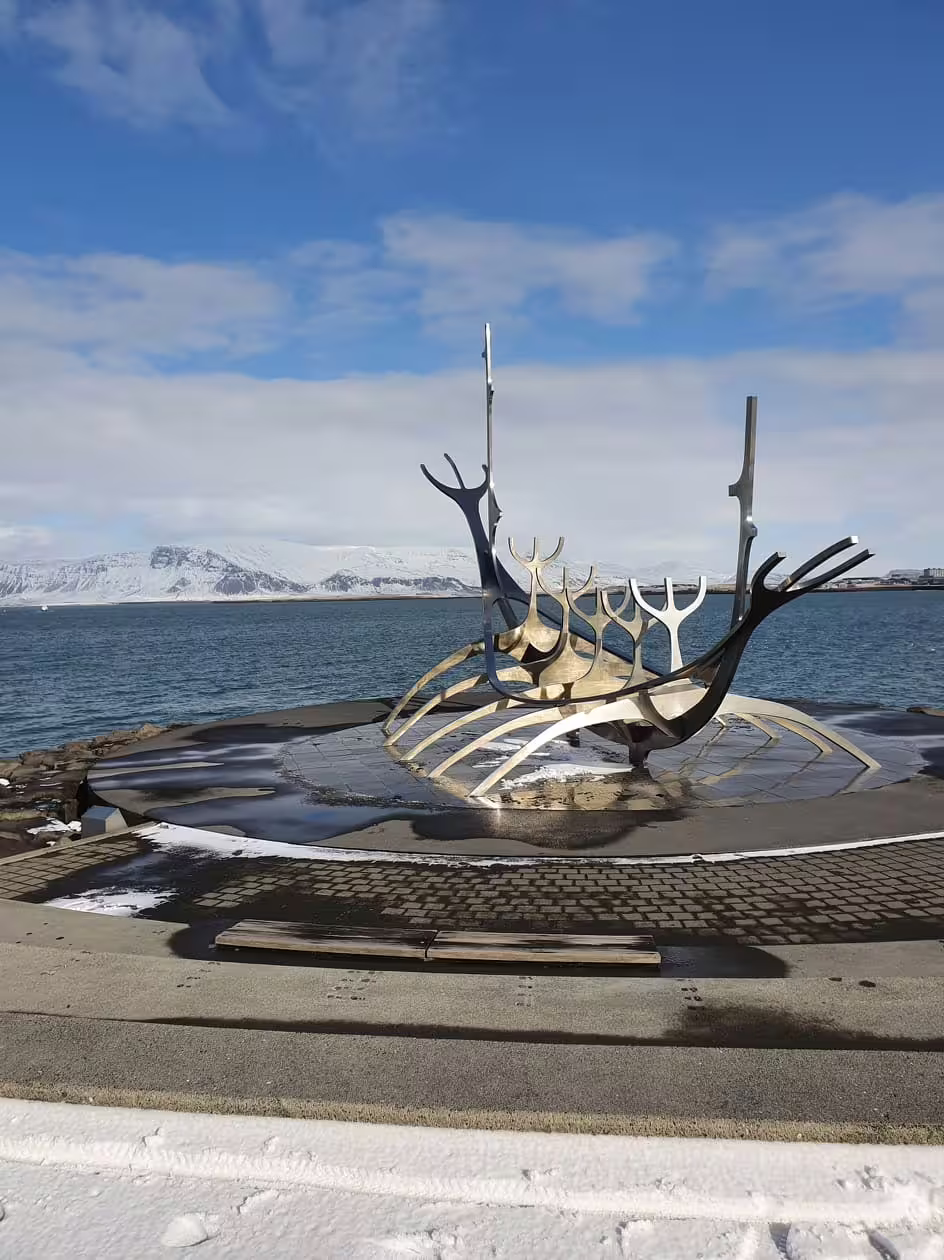 Sun Voyager steel Viking ship sculpture on Reykjavik waterfront with snow-capped mountains in background