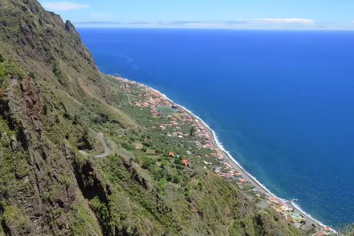 Scenic coastal view of lush cliffs and vibrant seaside village during the Sunny Southwest, Rum, Banana, Waterfall, and Lighthouse Discovery tour.