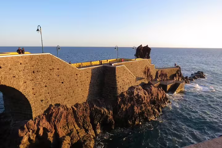Scenic coastal view of a historic stone lighthouse pier at sunset, perfect for Sunny Southwest tours with rum and banana adventures.
