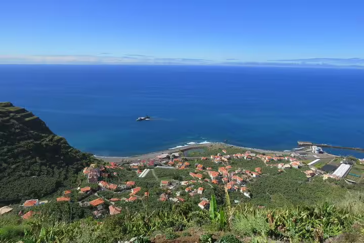 Scenic coastal view of a sunny village with lush greenery, ocean horizon, and vibrant blue skies on the Southwest Rum and Banana Tour.