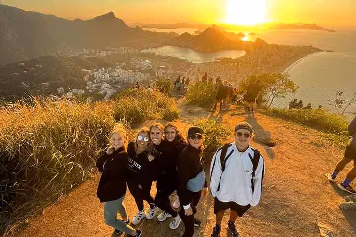 Group enjoying sunrise hike with breathtaking view over Rio de Janeiro's Two Brothers Mountain.
