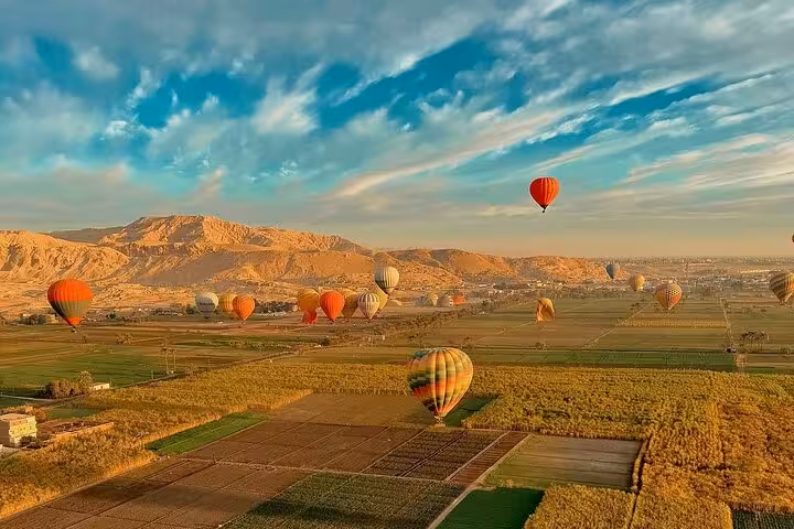 Sunrise hot air balloon ride over Luxor West Bank fields and desert hills, with hotel pickup and drop-off