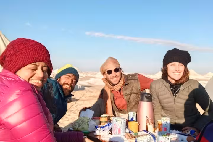 Group of friends enjoying a sunny outdoor breakfast after a hot air balloon ride over Luxor West Bank.