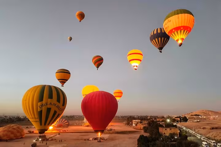 A fleet of colorful hot air balloons gracefully soar above Luxor West Bank during a serene sunrise adventure.