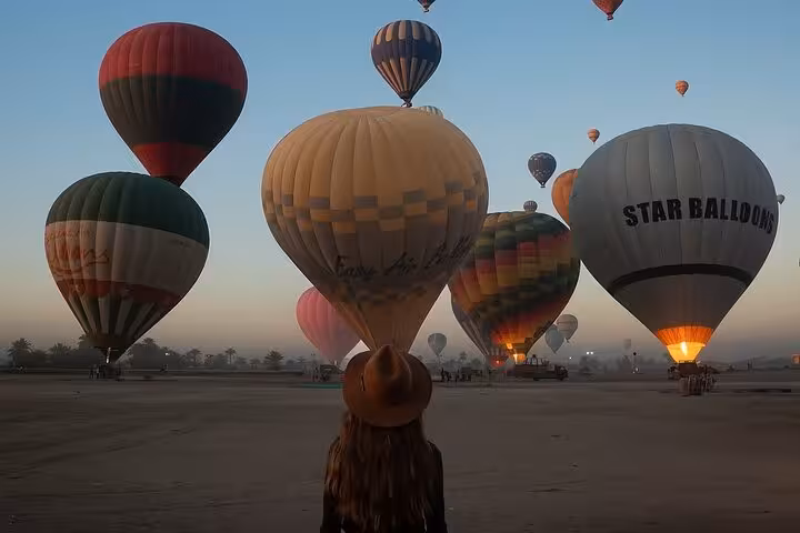 Traveler watching hot air balloons inflate at dawn in Luxor, Egypt, for sunrise balloon ride with pickup