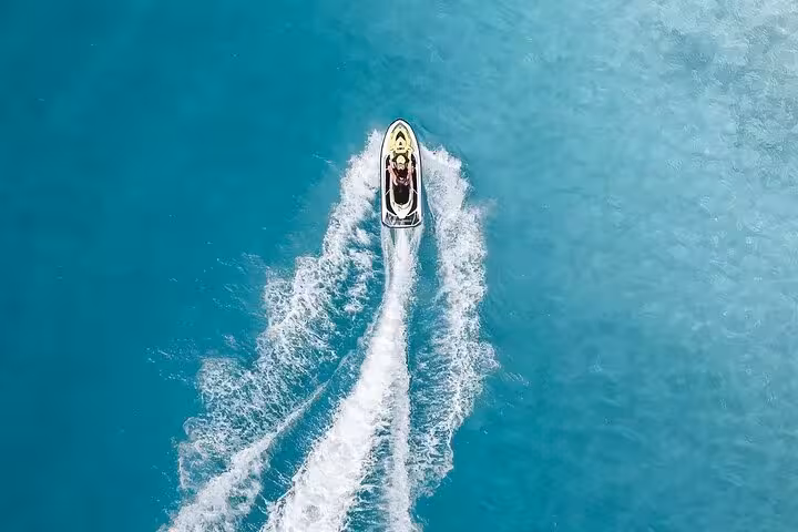 Aerial view of a jet ski cutting through turquoise waters in Antibes, leaving a white wake trail