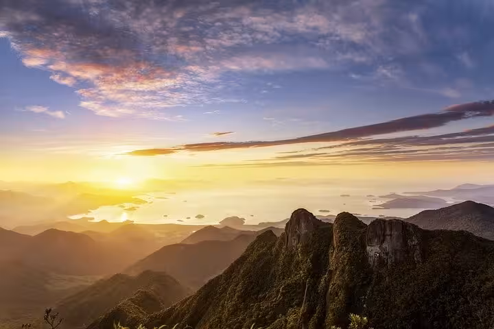 Golden sunrise illuminating Pedra da Macela, Paraty, with stunning panoramic views of mountains and sea.