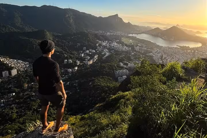 Man enjoying breathtaking sunrise view over Rio de Janeiro from Two Brothers peak, ideal for guided sunrise walks.