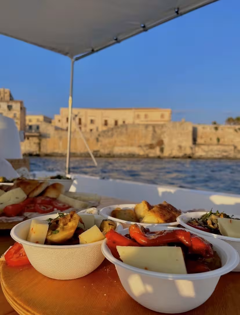 Gourmet appetizers served on a boat during the Sunset Aperitif Tour, with historic waterfront views in the background.