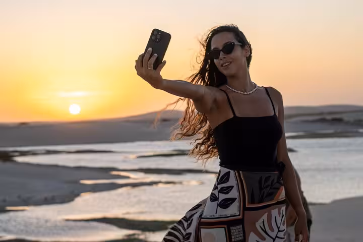 Traveler taking a selfie at sunset over Jericoacoara dunes and lagoons, highlight of the sunset ATV tour