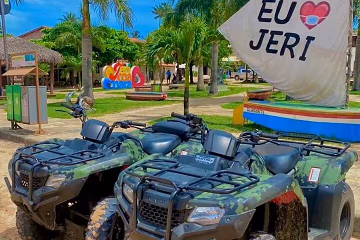 Camouflage ATVs parked by “Eu amo Jeri” sign, starting point for Jericoacoara sunset quad bike tour