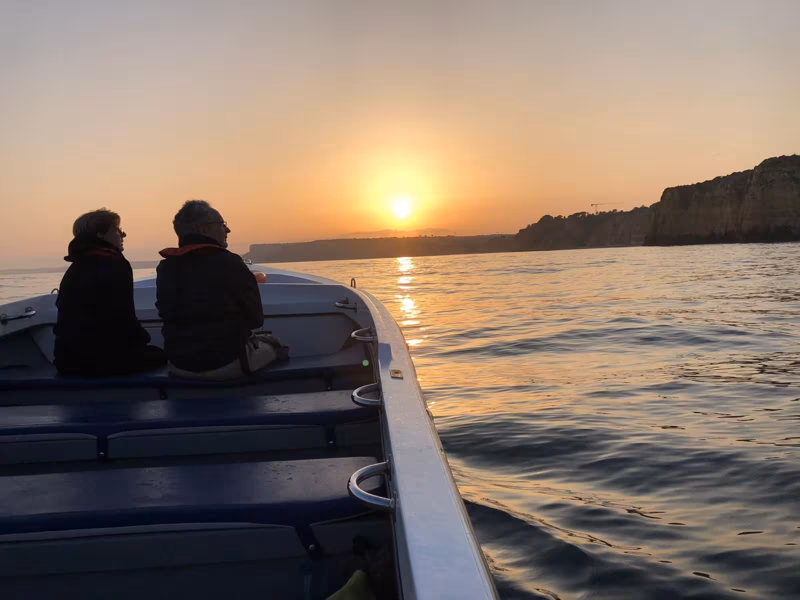 Couple enjoying a private sunset boat tour in Lagos near Ponta da Piedade caves with golden ocean views