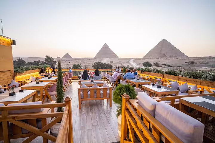 Great Pyramid Inn terrace dining at sunset with guests facing Giza Pyramids before Sound and Light Show, Cairo