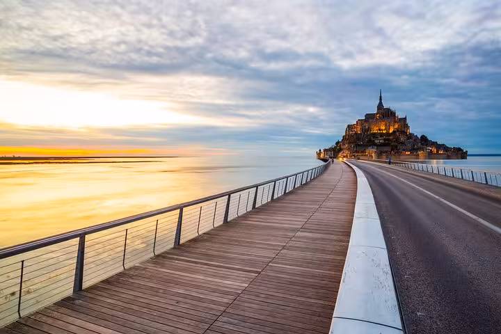 Sunset boardwalk and causeway leading to Mont Saint Michel, scenic stop on small group day tour with luxury van