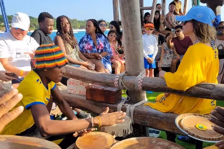 Tourists on a dhow engage with local music and culture during a sunset cruise in Kendwa, Zanzibar.