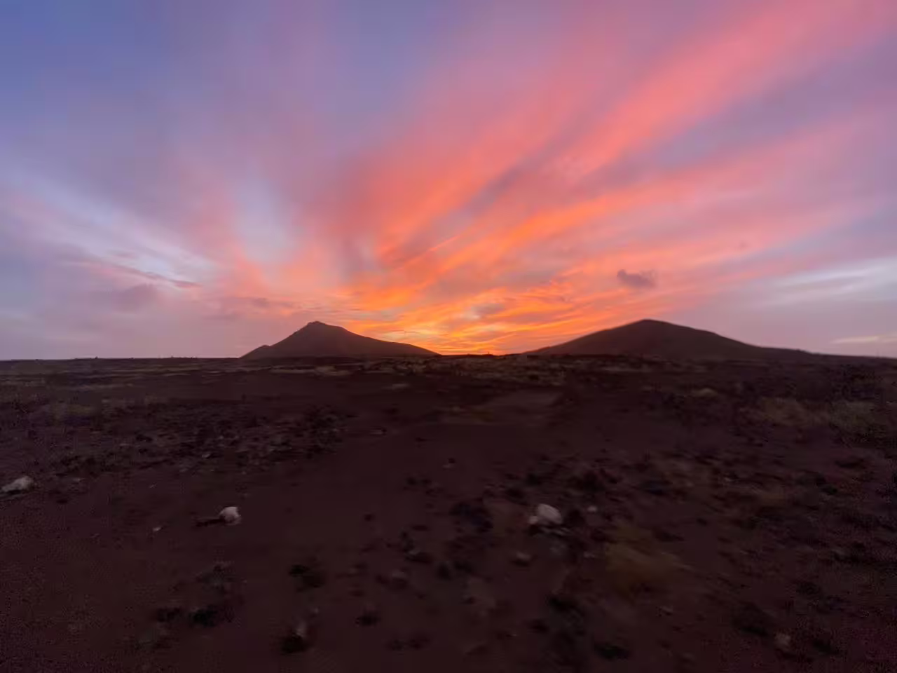 Guided Mount Lion sunset hike across volcanic landscape with dramatic pink-orange sky and twin peaks ahead