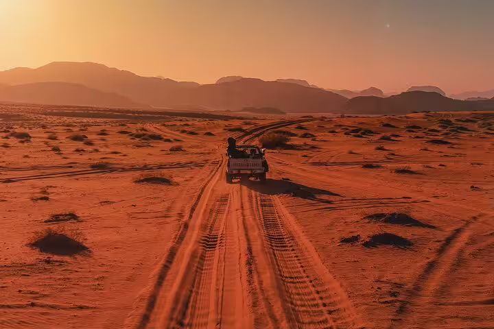 Sunset jeep ride across red desert tracks toward Jordan mountains, add-on adventure on Petra tour from Taba ferry