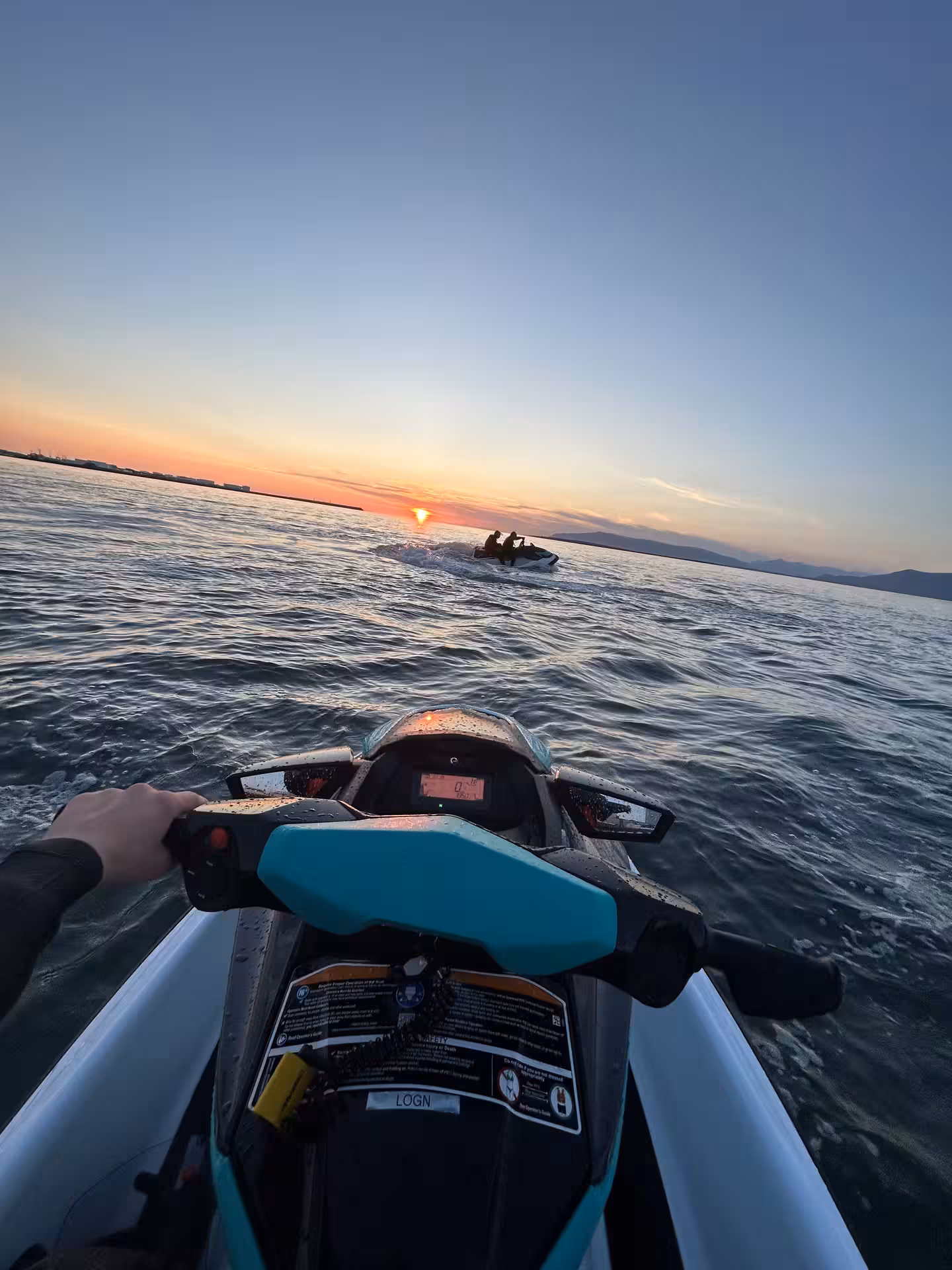 First-person view from a teal Sea-Doo jet ski on calm waters during a golden sunset in Reykjavik Bay