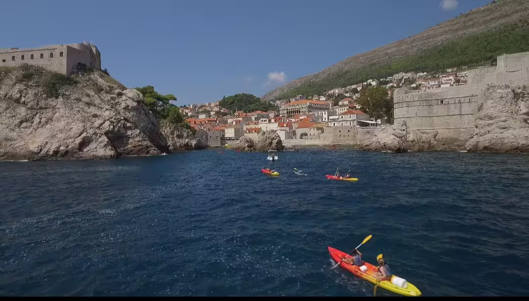 Sea kayaking near Dubrovnik Old Town walls, paddling to snorkel spots with water and wine at sunset