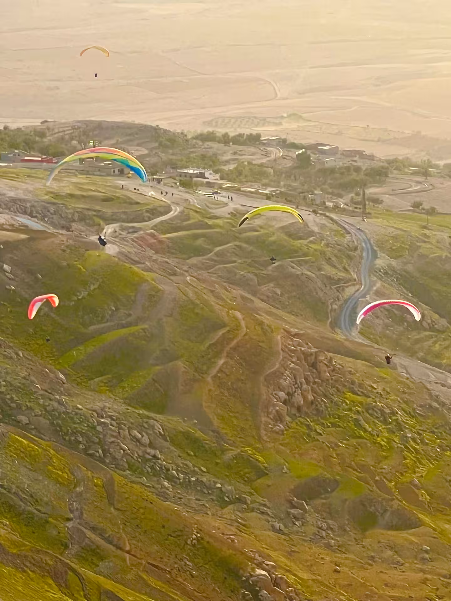 Multiple paragliders flying above the scenic Agafay Desert landscape near Marrakech.