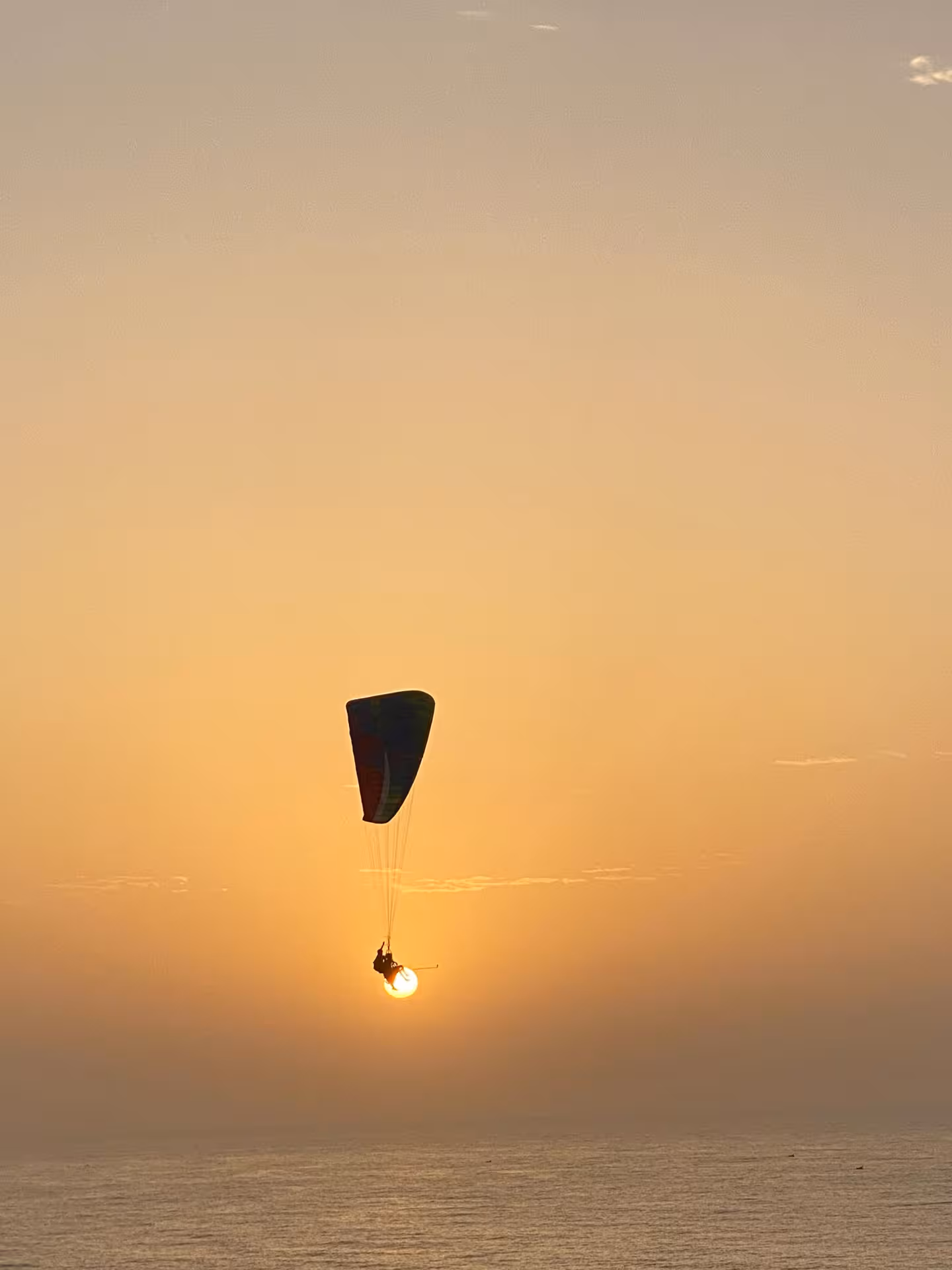 Paraglider silhouetted against a dramatic sunset over the Agafay Desert, Marrakech.