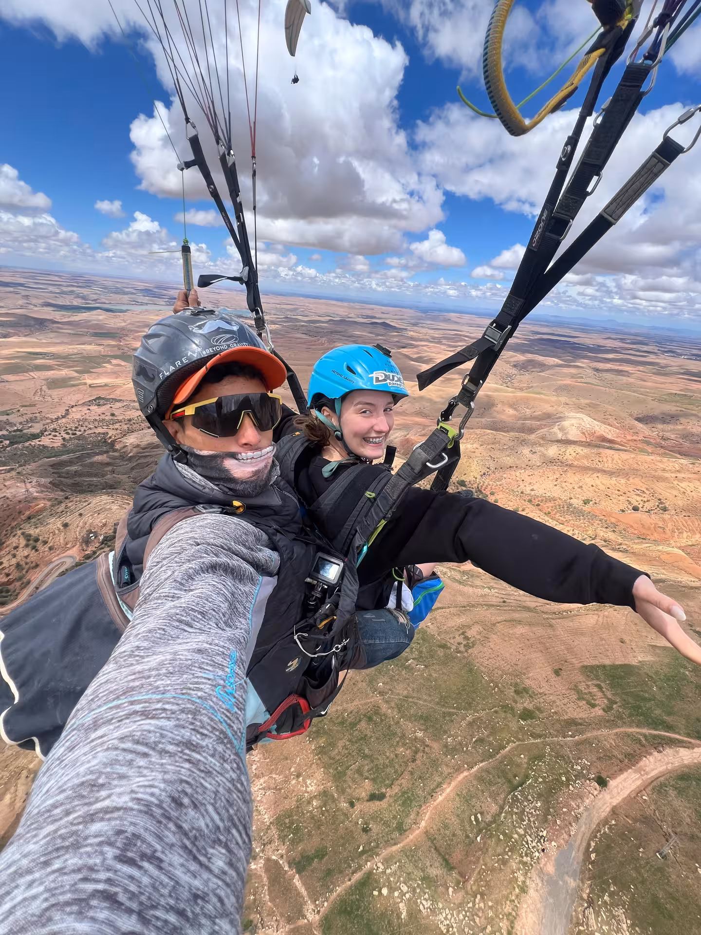 Tandem paragliding adventure over Agafay Desert with stunning views near Marrakech under a vibrant sky.