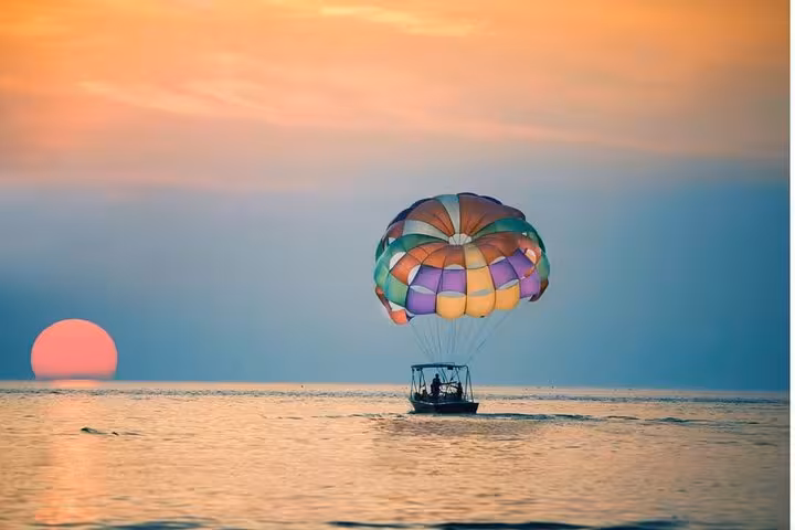 Sunset parasailing in Hurghada over the Red Sea, colorful canopy behind speedboat with private transfer