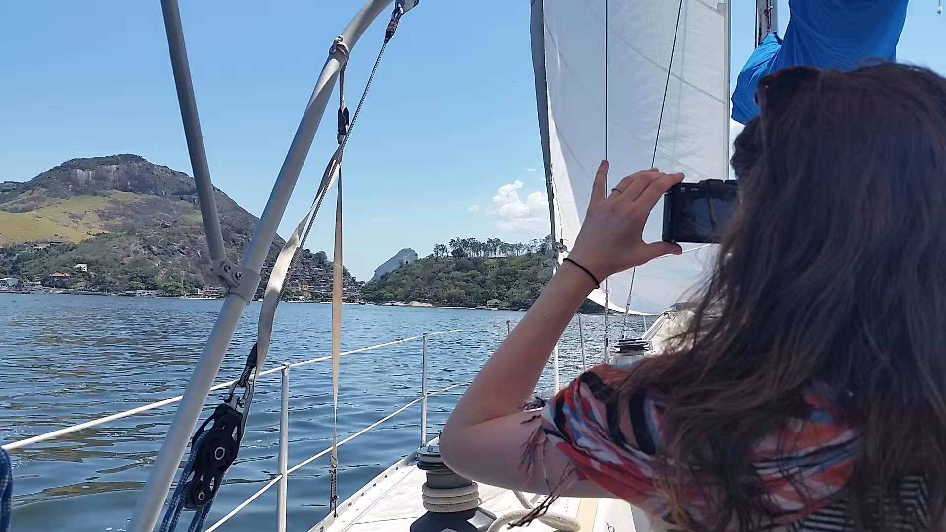 Traveler captures breathtaking coastal views from a sailboat tour in Rio de Janeiro's calm waters.