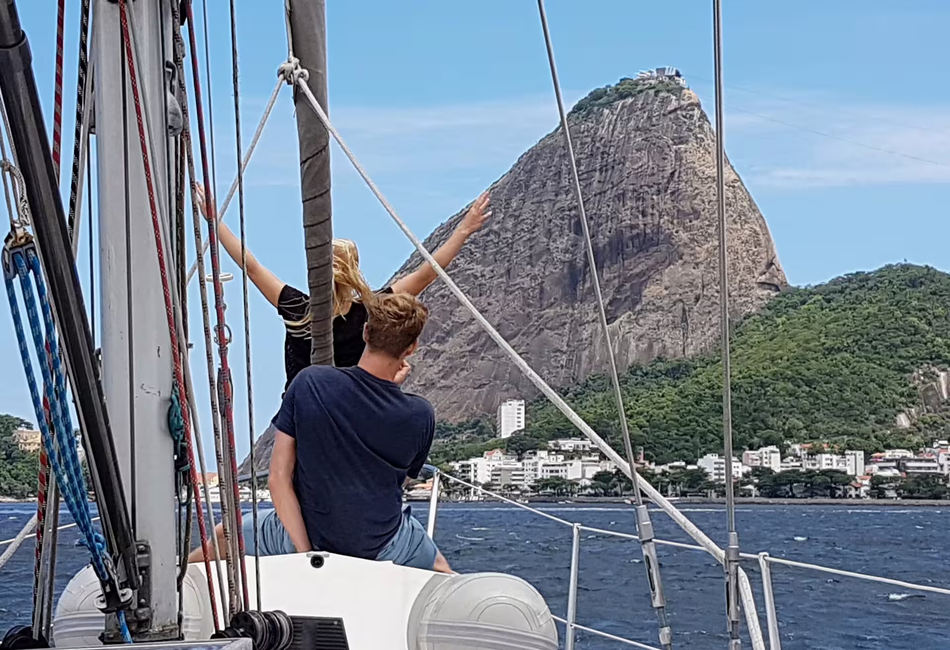 Tourists enjoy a scenic sailboat ride with stunning views of Sugarloaf Mountain in Rio de Janeiro.