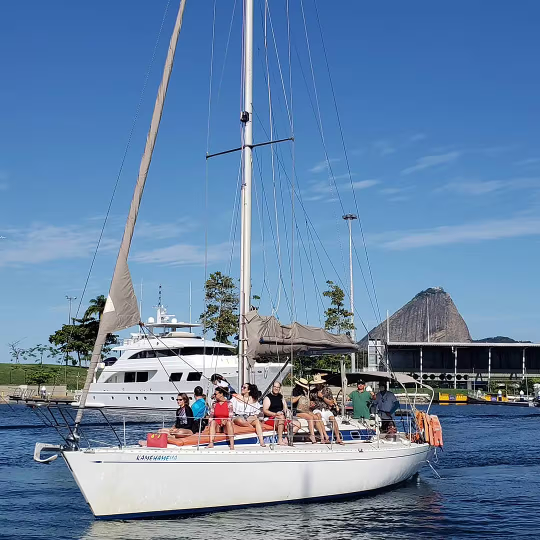 Tourists enjoying a yacht cruise with Sugarloaf Mountain backdrop in Rio de Janeiro, ideal for sunset views.