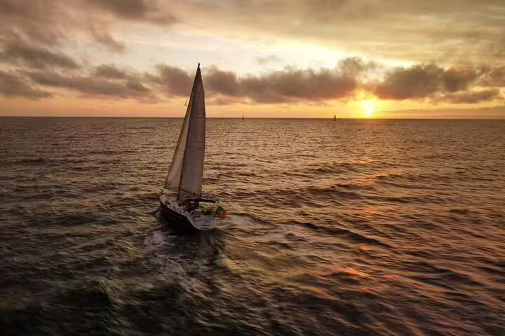 Private sailing cruise at sunset on Madeira's ocean, showcasing a serene view of golden skies and tranquil waters.