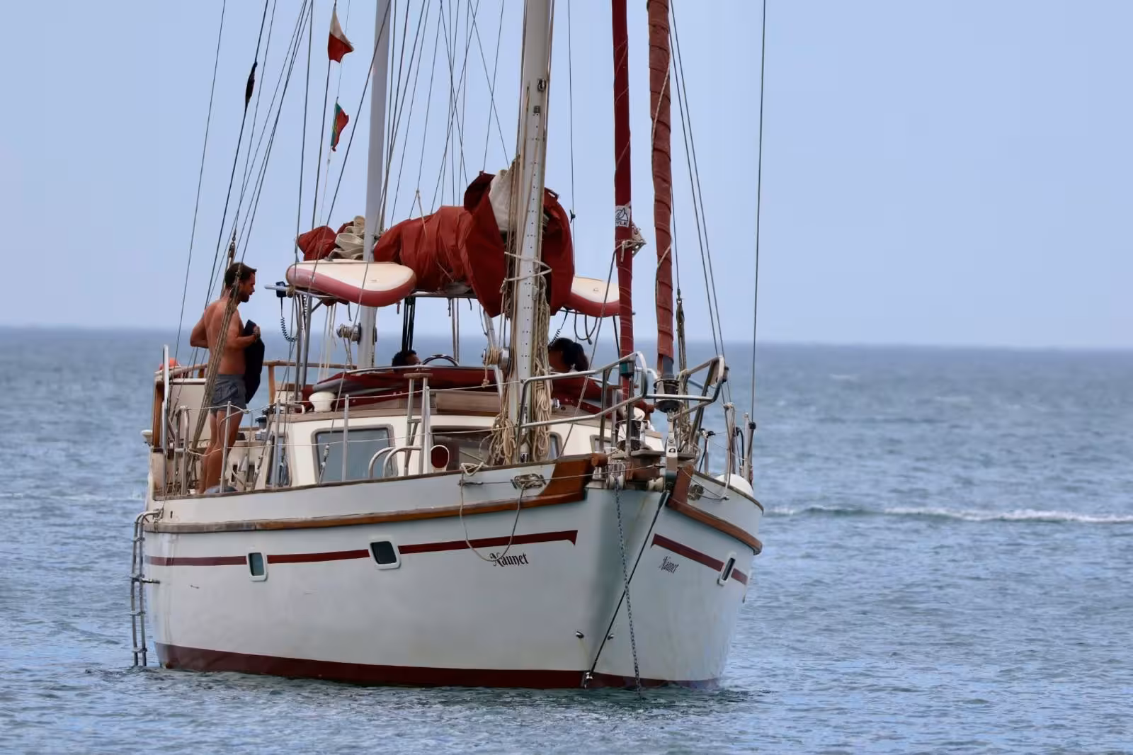 Classic white sailboat with red sails cruising Portimao waters on a romantic sunset sailing tour in Algarve