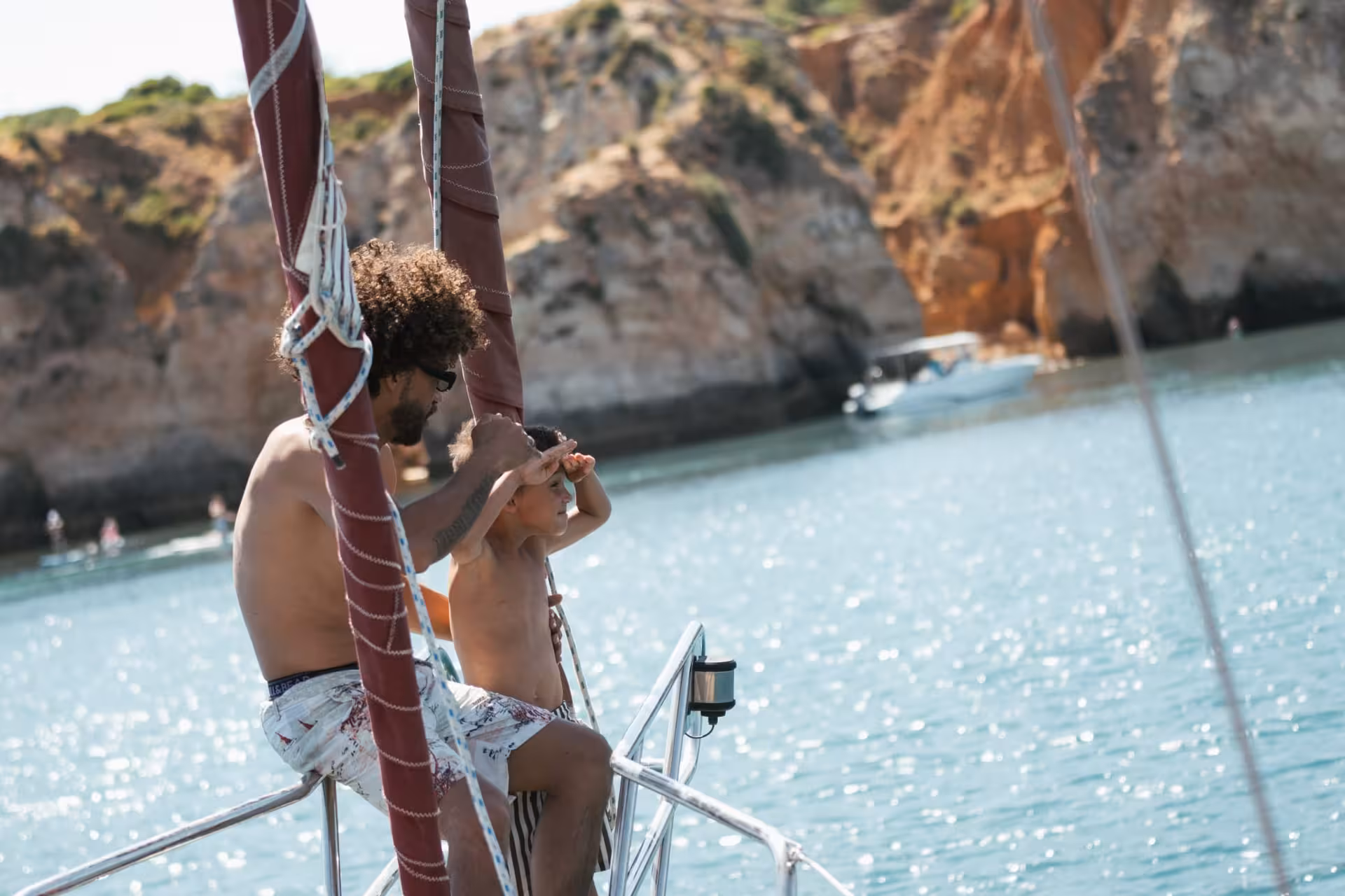 Father and child gazing at scenic Algarve sea cliffs during a romantic sunset sailing tour in Portimao with sparkling wine