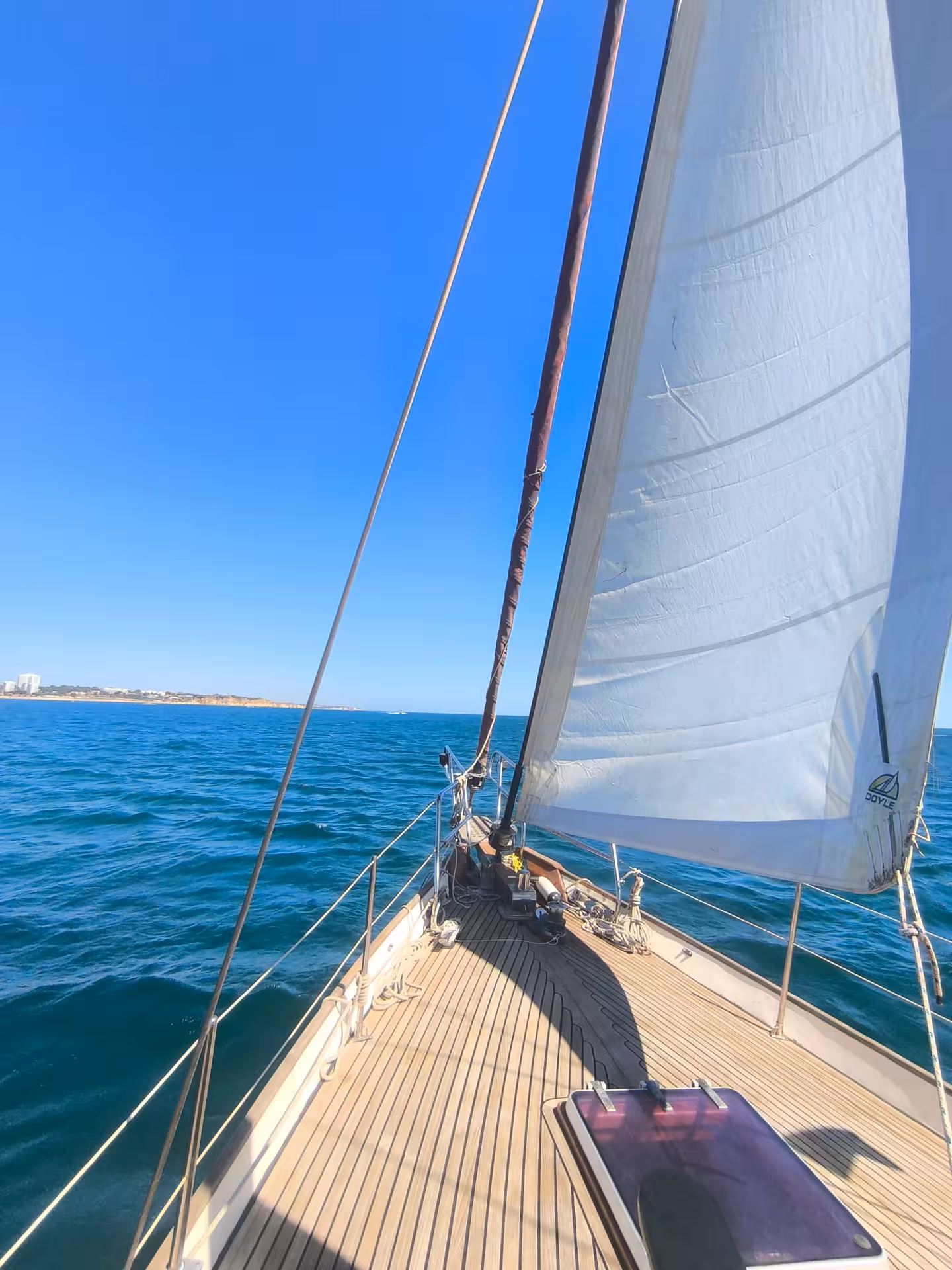 Teak deck and billowing white sail on a romantic sunset sailing tour in Portimao with sparkling wine
