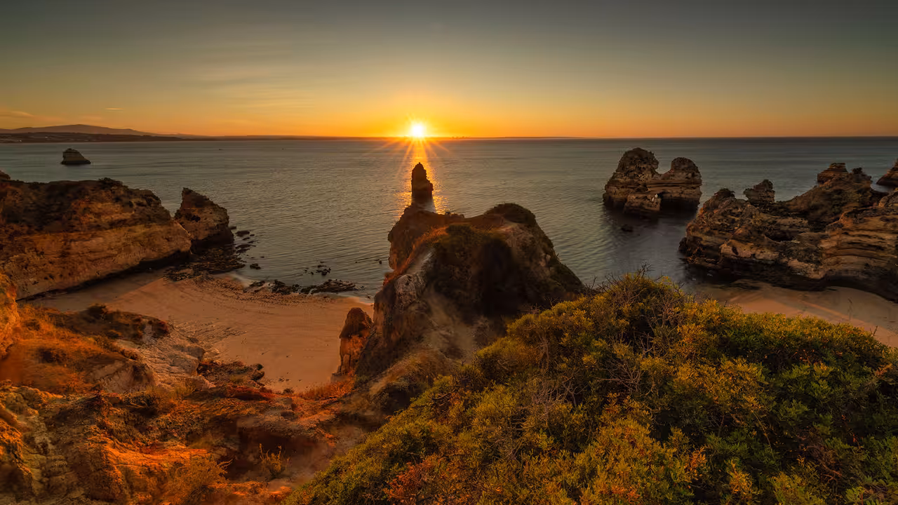 Sun setting behind dramatic sea cliffs and hidden coves, ideal coastal scenery for a sunset sailing tour adventure