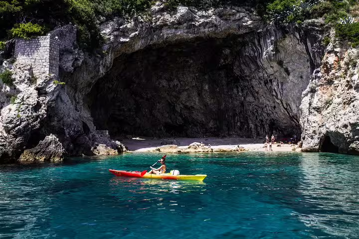 Sea kayak on turquoise water by a rocky cave beach, perfect for sunset kayaking and snorkeling with wine