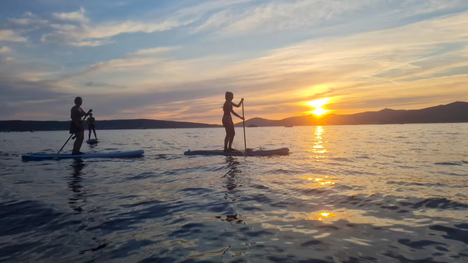 Sunset stand up paddleboarding near Split, Croatia, with paddlers silhouetted on calm Adriatic waters