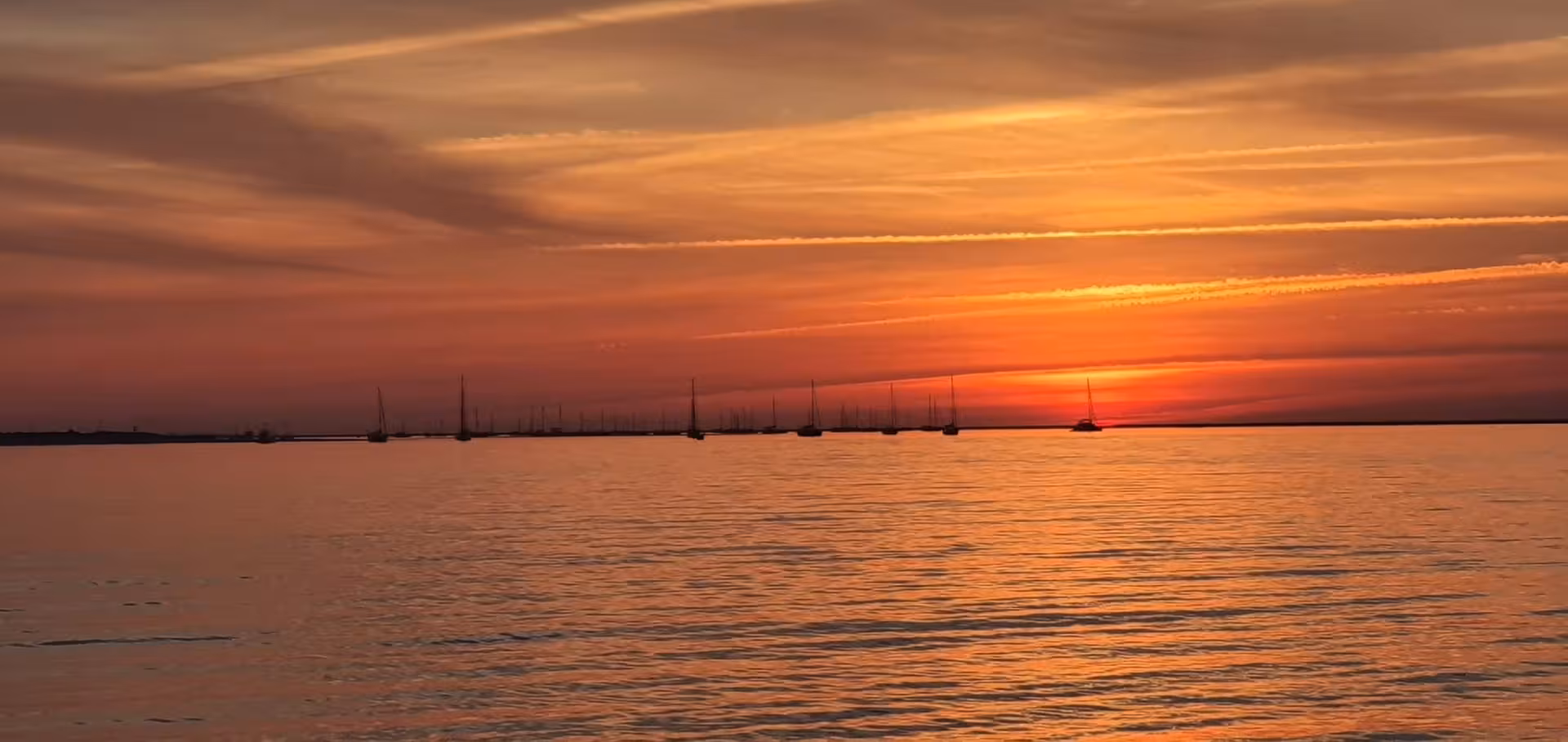 Serene sunset over calm ocean with silhouetted sailboats, perfect for a romantic Sunset Tour Privado experience.