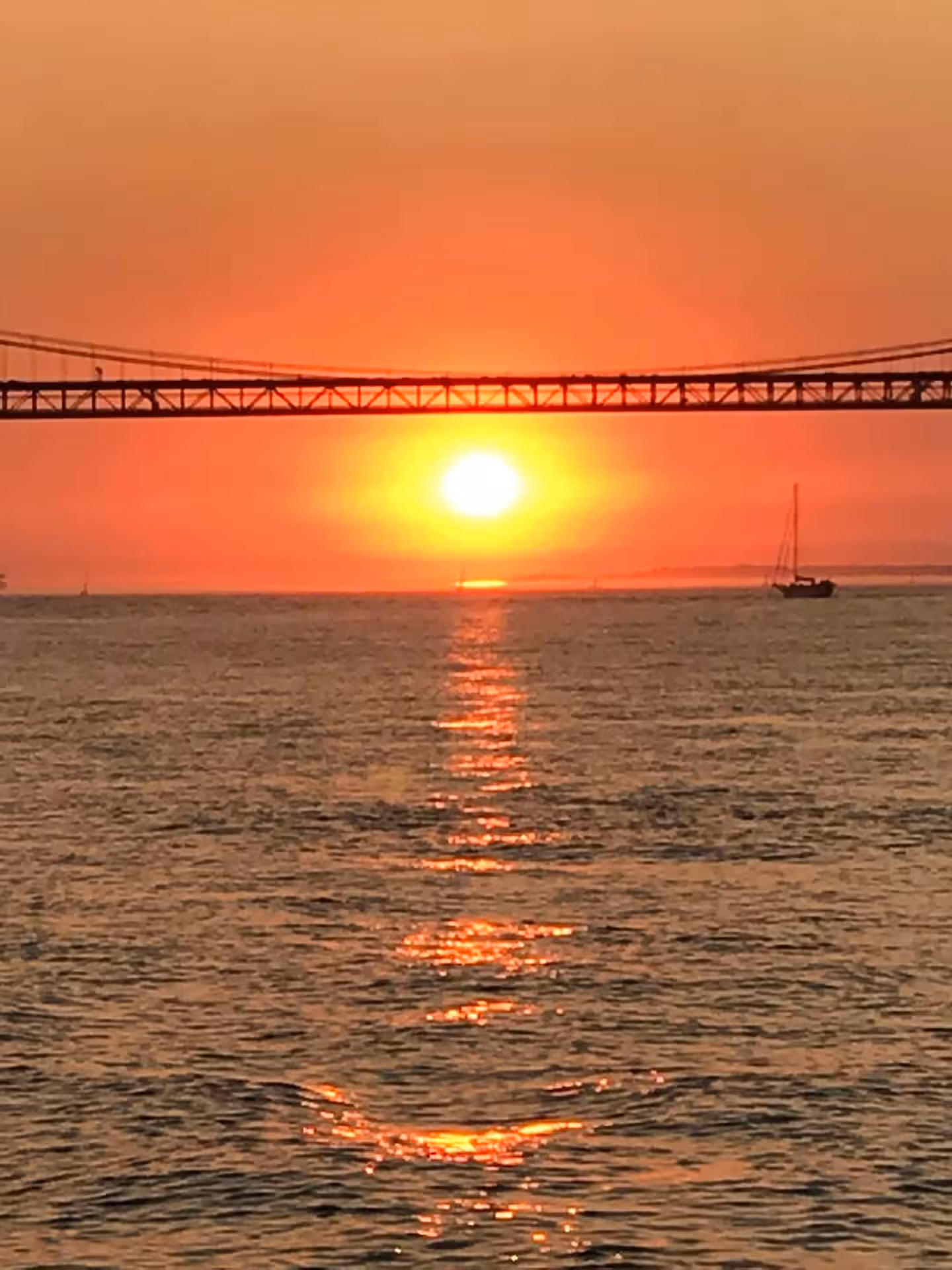 Golden sunset over Lisbon’s Tagus River beneath 25 de Abril Bridge on VIP catamaran wine cruise