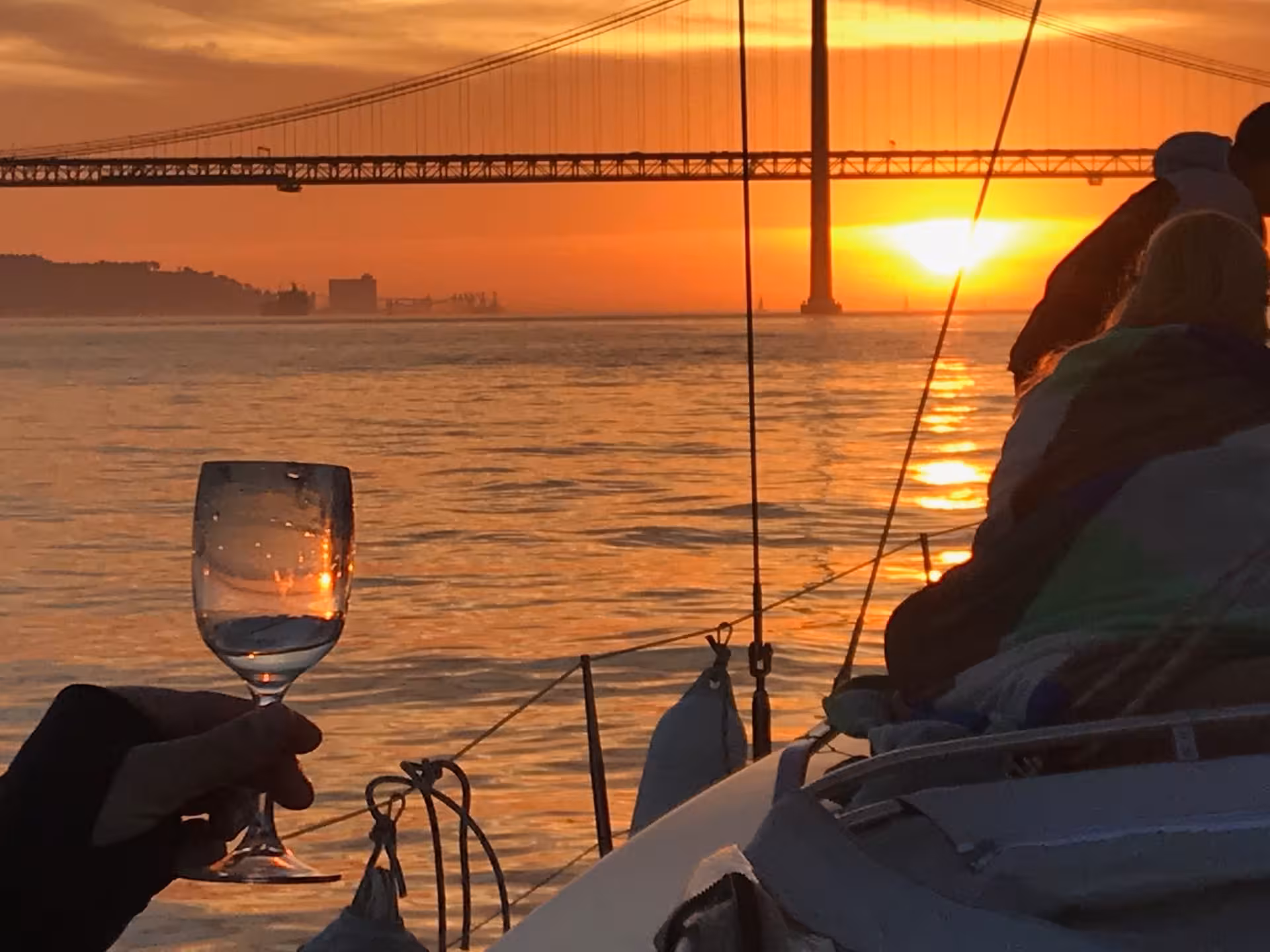 Toast with wine on a VIP catamaran at sunset by Lisbon’s 25 de Abril Bridge, Sunset & Wine cruise