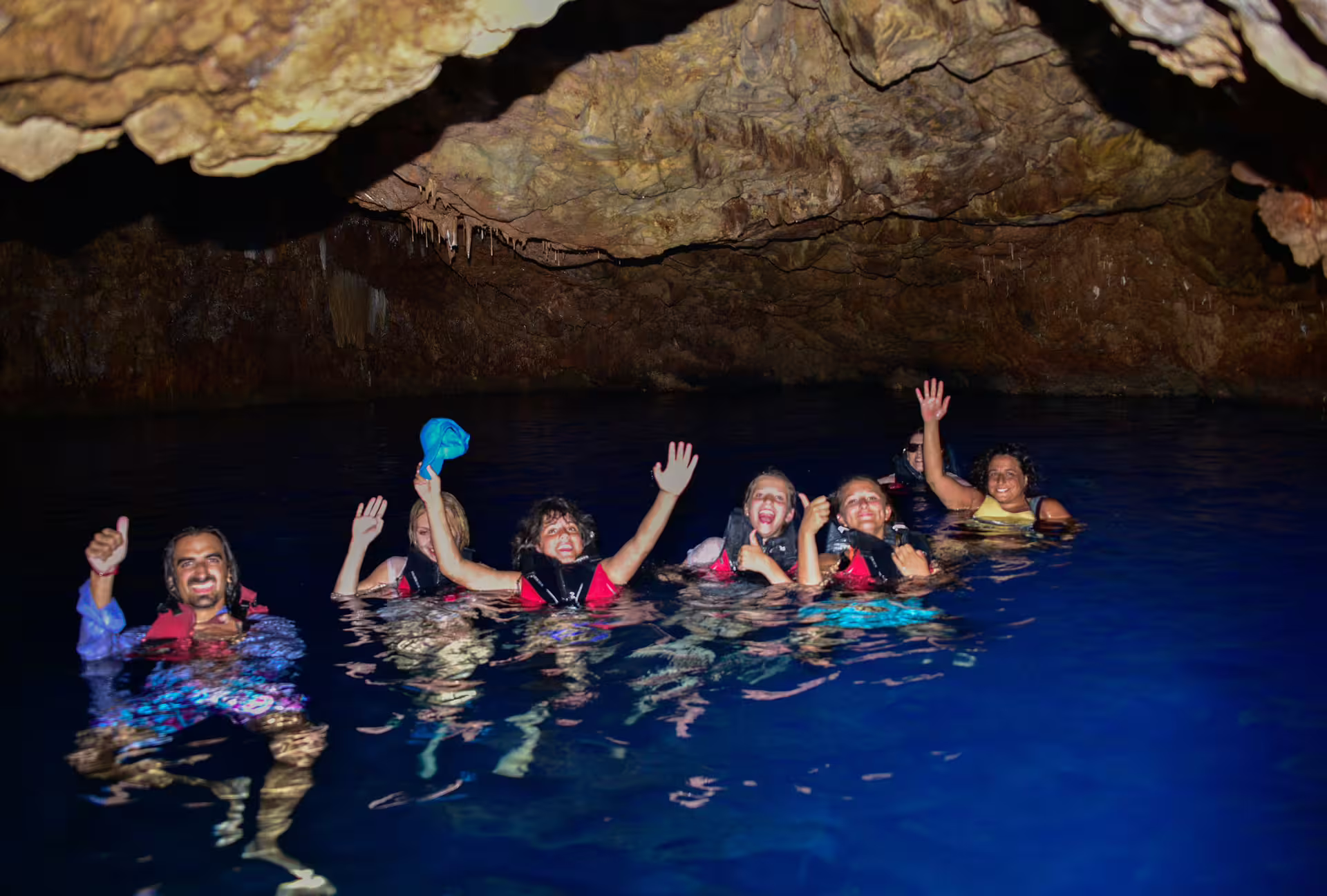 Group swimming in a sea cave during SUP in Kardamyli, Mani Peninsula, wearing life jackets in blue water