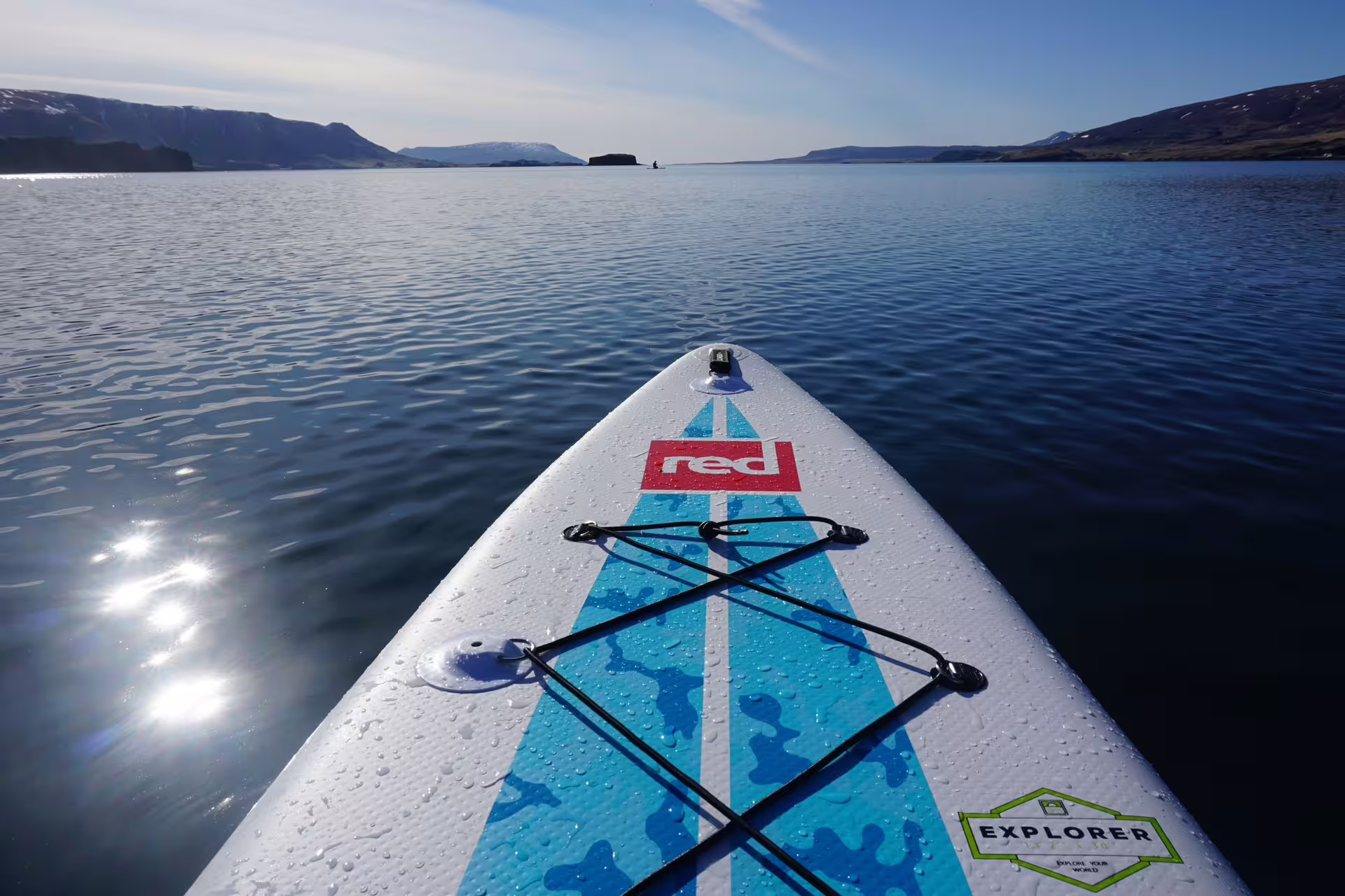 Paddle board gliding through serene waters of the Forgotten Fjords under a clear sky on a SUP adventure tour.