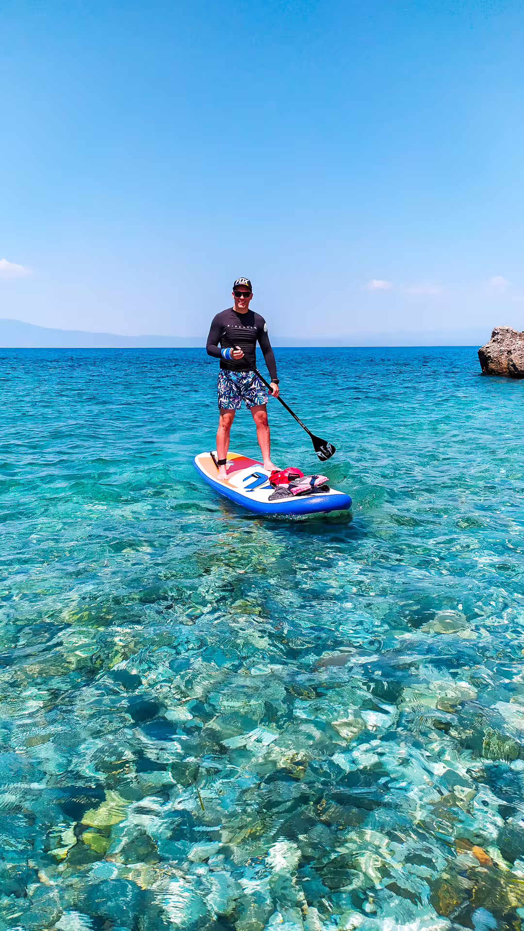 Stand up paddleboarder gliding over crystal-clear water on a SUP tour in Kalamata, Messinia coast