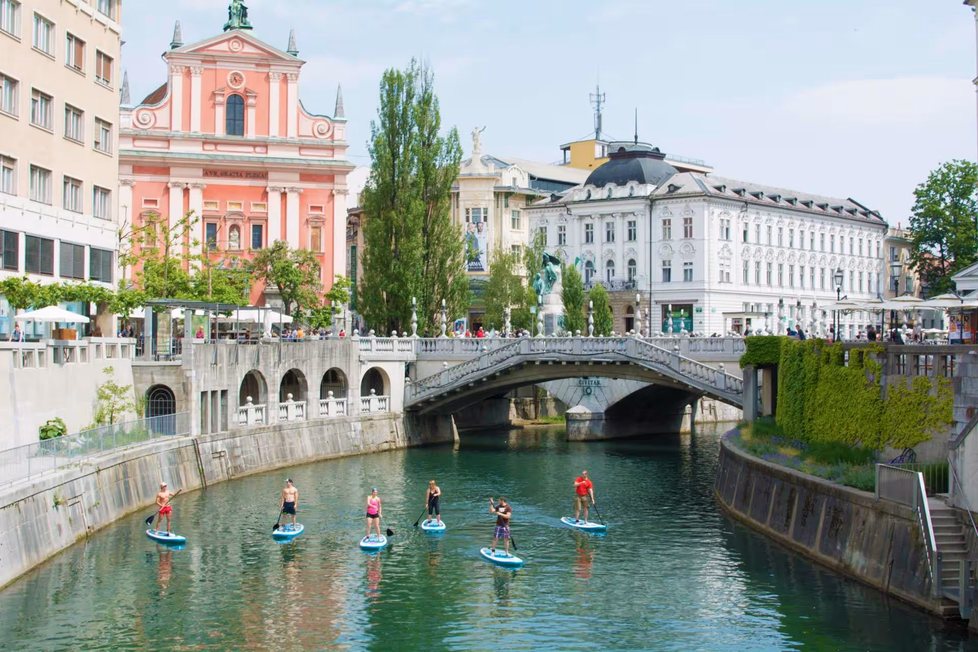 Stand up paddleboarding on Ljubljana River near Triple Bridge, scenic SUP Ljubljana city tour in Slovenia