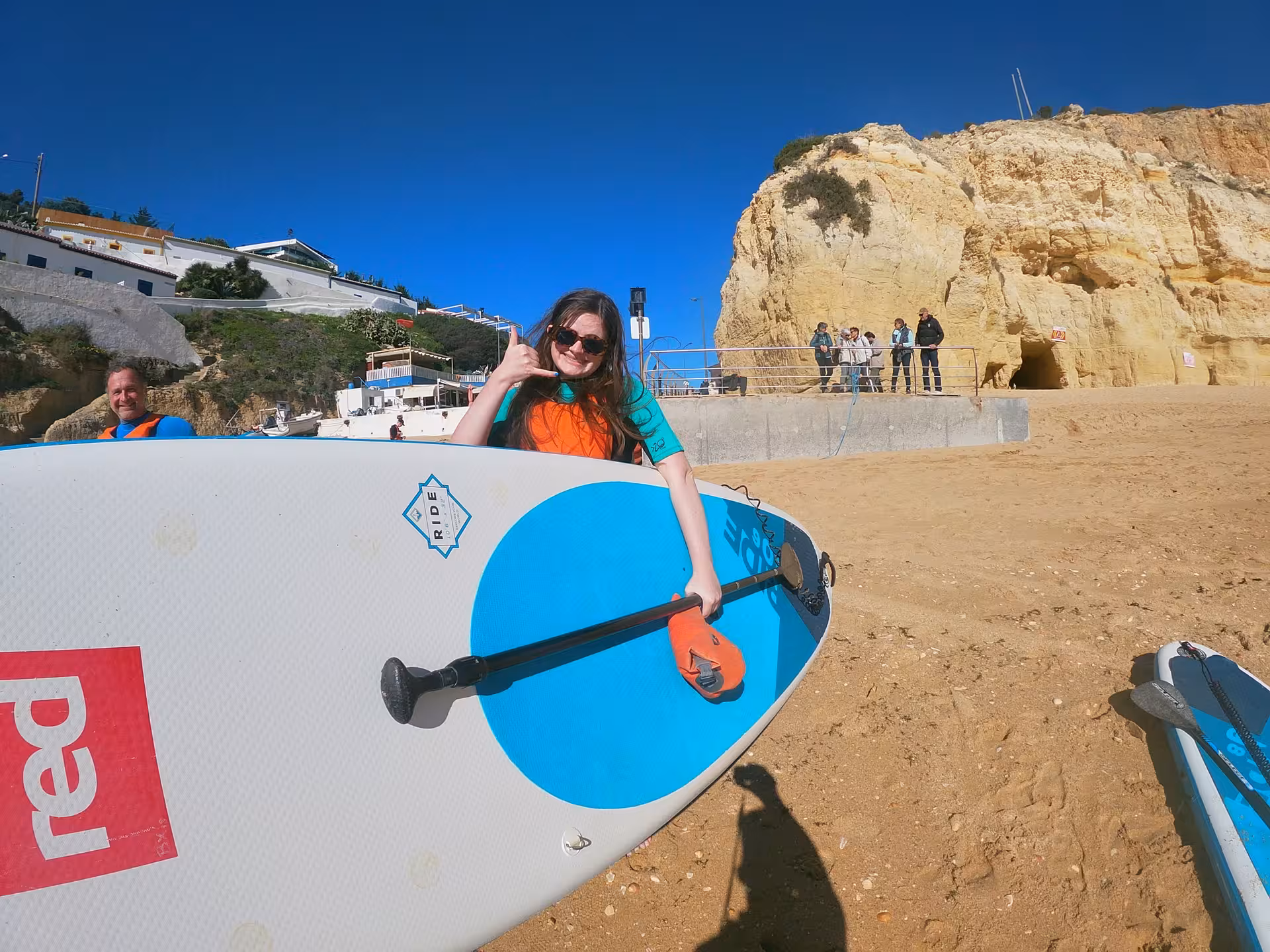 Smiling paddler holding SUP on sandy Algarve beach after stand up paddle tour along Portugal’s scenic cliffs