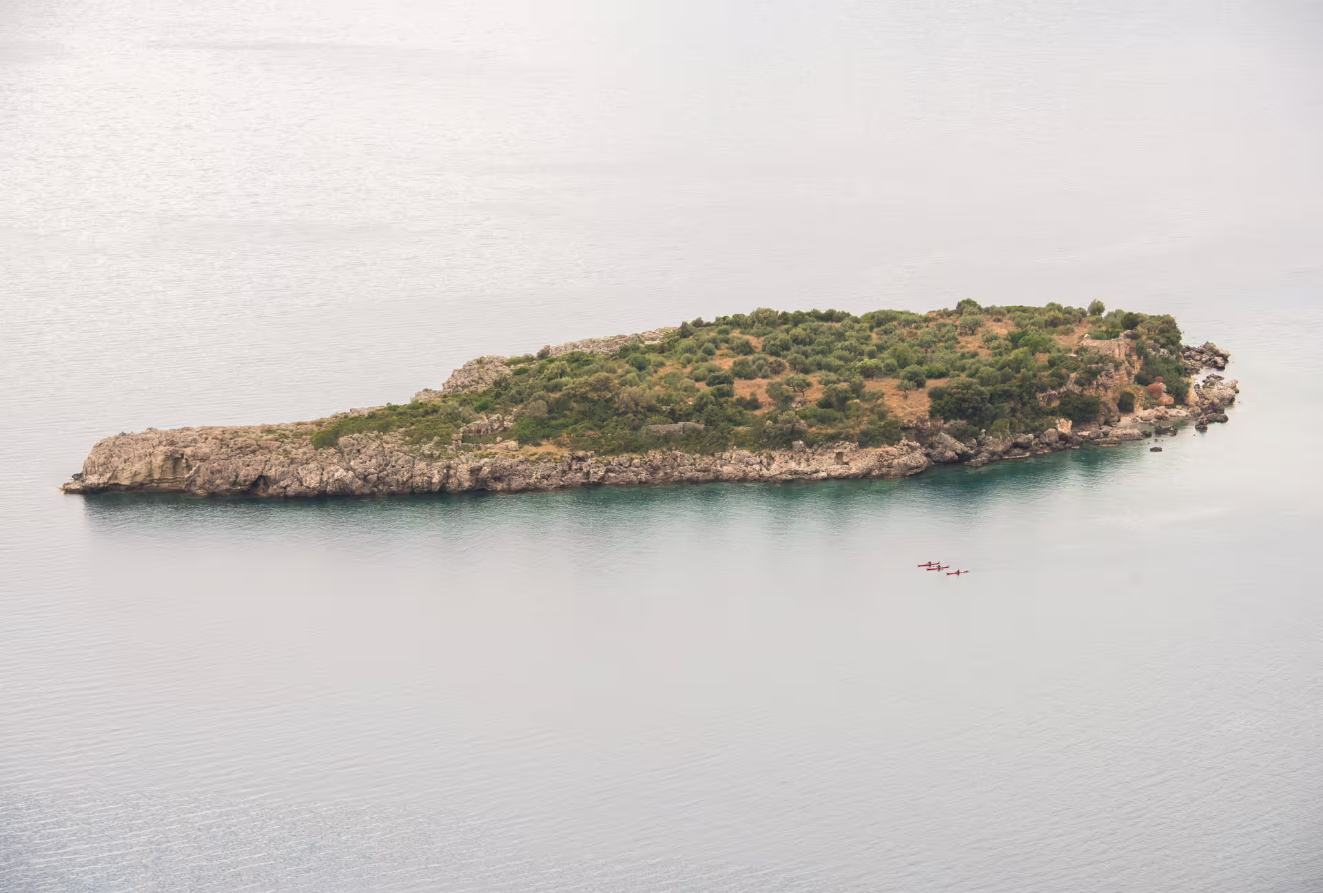Aerial view of islet near Kardamyli with paddlers on a SUP tour, exploring calm turquoise waters in Mani