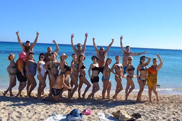 Happy group photo on sandy beach at Super Giftun Island, Red Sea day trip with snorkeling and swimming
