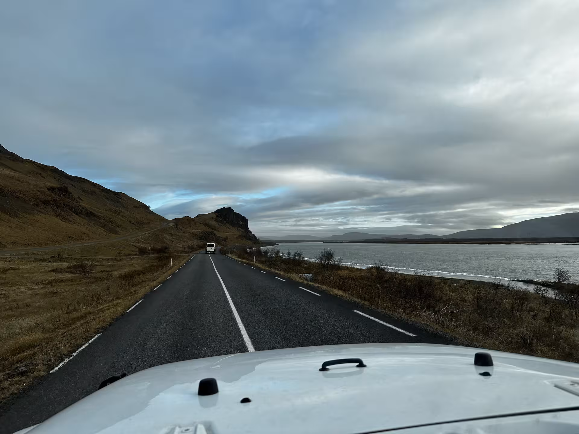 Super jeep driving coastal road toward Landmannalaugar with mountains and fjord in Iceland