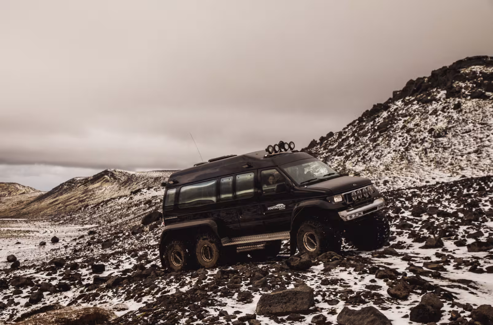 Black 6x6 super jeep navigating snowy rocky terrain on Eyjafjallajokull glacier Iceland
